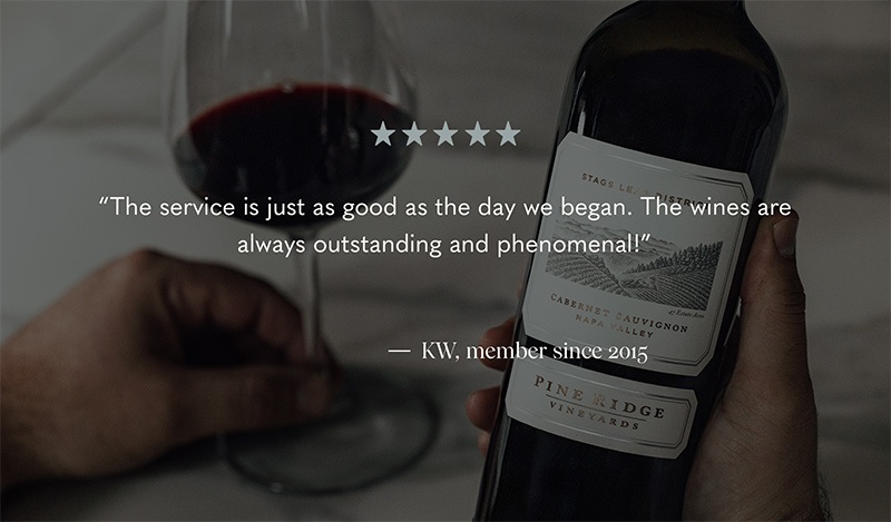 A person holds a bottle of Pine Ridge Vineyards Cabernet Sauvignon next to a glass of red wine on a marble surface. Text reads: The service is just as good as the day we began. The wines are always outstanding and phenomenal! - KW, member since 2015.