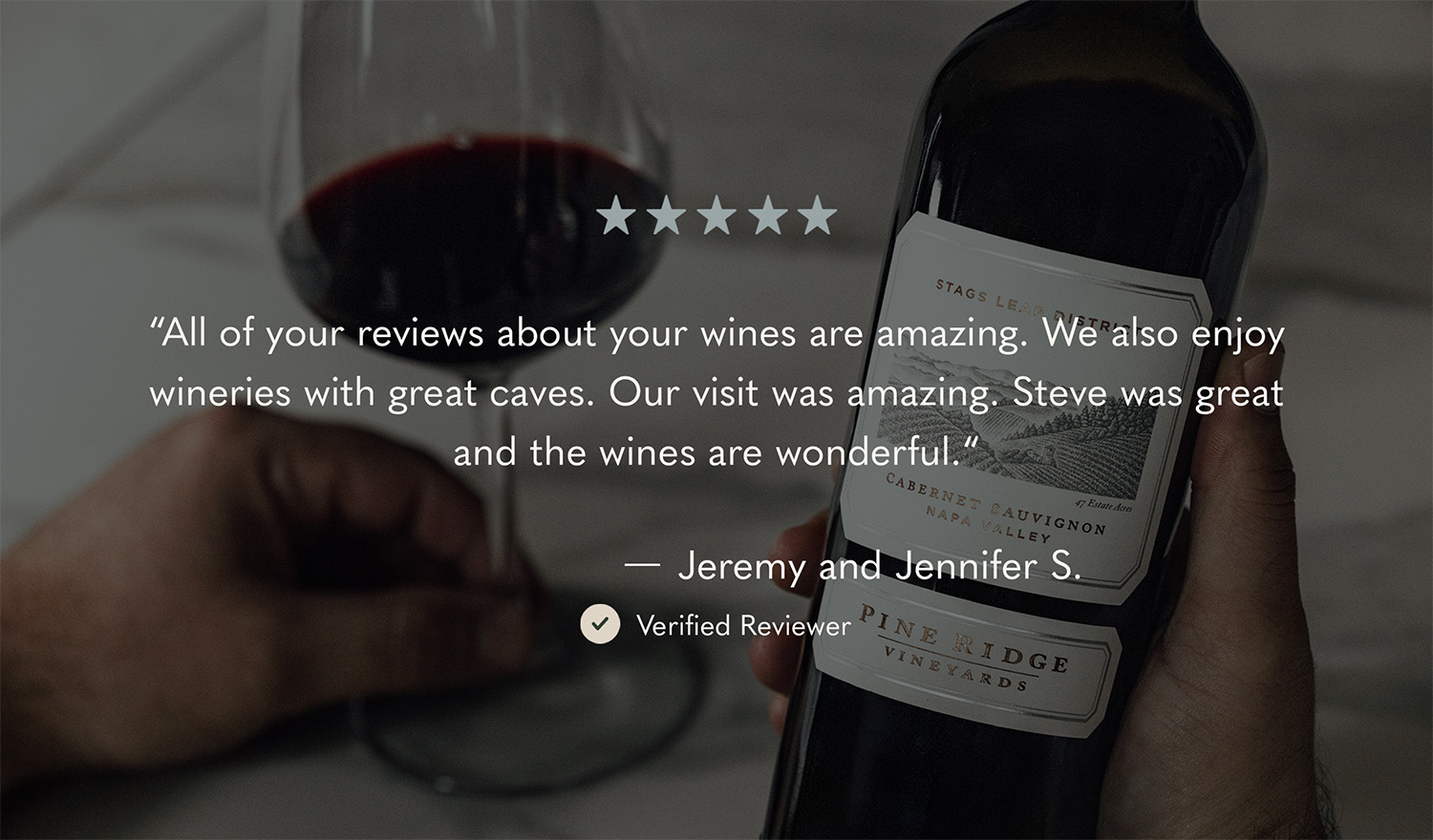A hand holds a wine glass filled with red wine. In the background, there is a wine bottle with a partially visible label. The image features a five-star review praising the wine and service from Jeremy and Jennifer S., labeled as a verified reviewer.