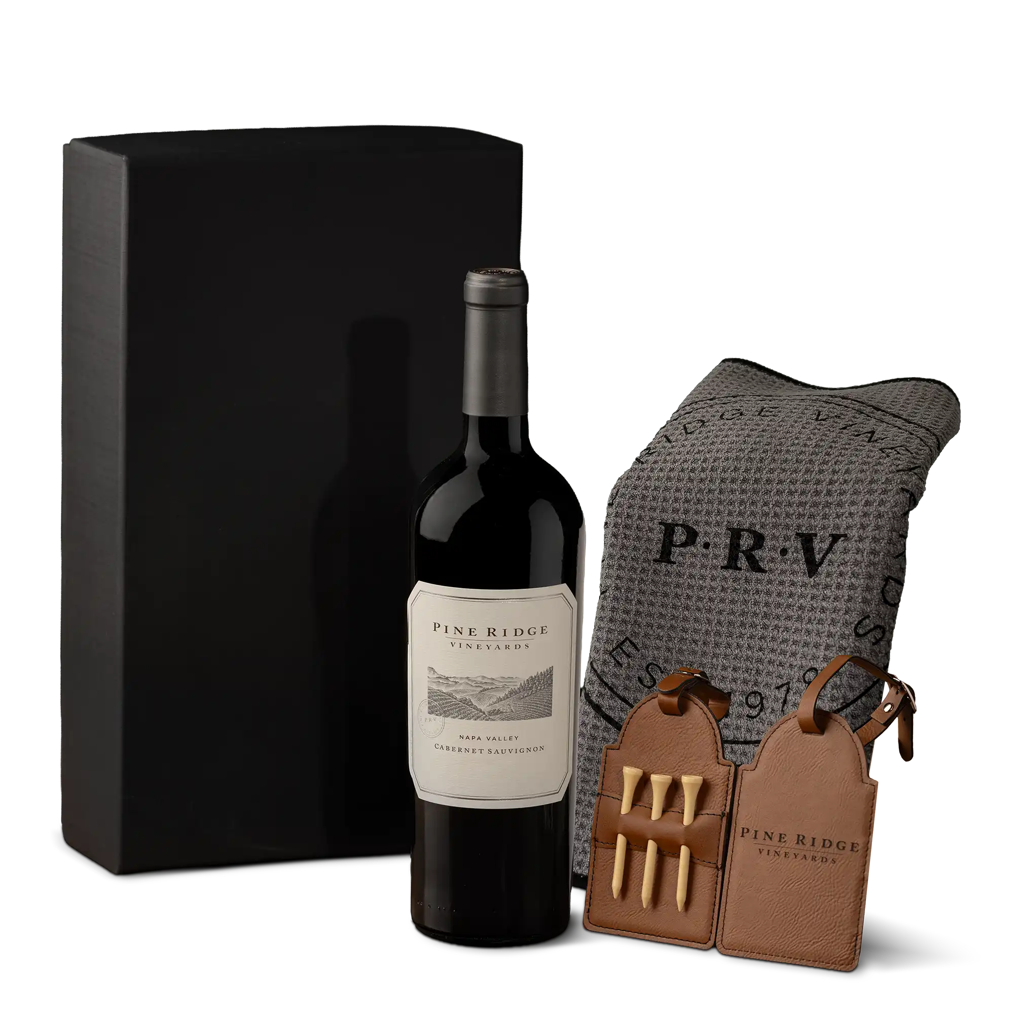 A bottle of Pine Ridge Vineyards wine stands next to a black box, a gray textured blanket with PRV initials, and two leather cases containing four wooden golf tees each—an exquisite Bordeaux Luxe Wine Gift for any discerning connoisseur.