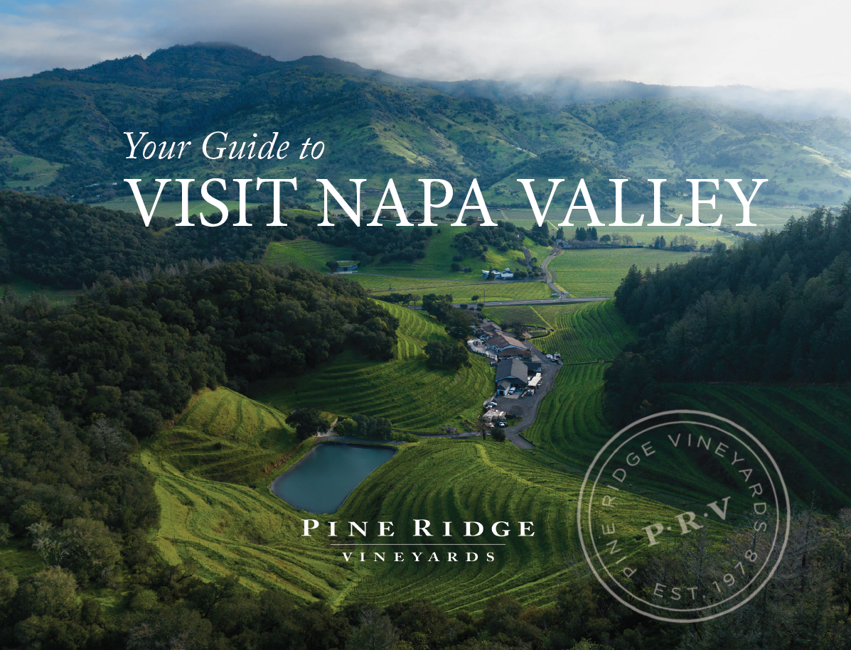 Aerial view of Pine Ridge Vineyards in Napa Valley with terraced vineyards surrounded by trees. The text reads Your Guide to Napas Wild Side and Pine Ridge Vineyards with a circular logo in the bottom right corner.