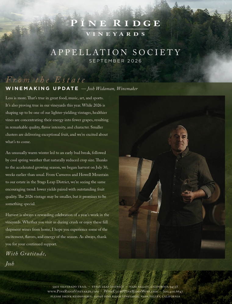 A man stands holding a glass of red wine in a dimly lit room with wine barrels. The image includes text about Pine Ridge Vineyards winemaking update and information on the 2026 Appellation Society.